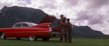Movie still from “3000 Miles to Graceland” (2001), directed by Demian Lichtenstein – A woman and two children standing next to a red car; Wide shot, Low angle