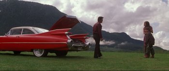 Movie still from “3000 Miles to Graceland” (2001), directed by Demian Lichtenstein – A man standing in front of a red car in a field; Extreme Wide shot, Low angle