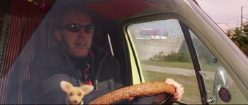 Movie still from “3000 Miles to Graceland” (2001), directed by Demian Lichtenstein – A man driving a car with a dog sitting in the passenger seat; Close Up shot, Low angle