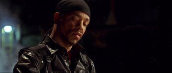 Movie still from “3000 Miles to Graceland” (2001), directed by Demian Lichtenstein – A person wearing a black shirt and a black hat; Close Up shot, Low angle