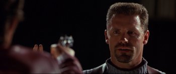 Movie still from “3000 Miles to Graceland” (2001), directed by Demian Lichtenstein – A person holding a gun in a dark room; Close Up shot, Low angle