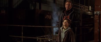 Movie still from “3000 Miles to Graceland” (2001), directed by Demian Lichtenstein – A man standing next to a young boy in front of a building; Medium shot, Low angle