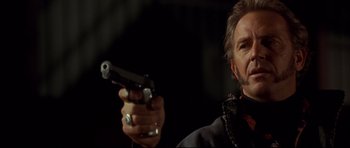 Movie still from “3000 Miles to Graceland” (2001), directed by Demian Lichtenstein – A man holding a gun while standing in a dark room; Close Up shot, Low angle