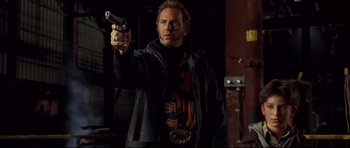 Movie still from “3000 Miles to Graceland” (2001), directed by Demian Lichtenstein – A man holding a gun while standing in a dark room; Medium shot, Low angle