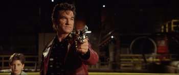 Movie still from “3000 Miles to Graceland” (2001), directed by Demian Lichtenstein – A man holding a gun while standing in front of a building; Medium shot, Low angle