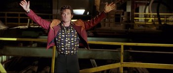 Movie still from “3000 Miles to Graceland” (2001), directed by Demian Lichtenstein – A man wearing a red jacket and black pants standing next to a yellow fence; Medium shot, Low angle