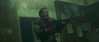 Movie still from “3000 Miles to Graceland” (2001), directed by Demian Lichtenstein – A man holding a gun while standing in front of a building; Medium shot, Low angle