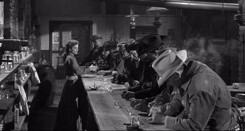 Movie still from “3:10 to Yuma” (1957), directed by Delmer Daves – A group of people sitting at a long table; Wide shot, High angle
