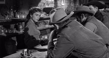Movie still from “3:10 to Yuma” (1957), directed by Delmer Daves – An old photo of a man and a woman sitting at a table; Medium shot, Over the shoulder angle