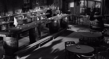 Movie still from “3:10 to Yuma” (1957), directed by Delmer Daves – A man sitting at the bar of a restaurant; Wide shot, High angle