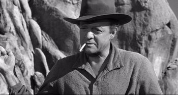 Movie still from “3:10 to Yuma” (1957), directed by Delmer Daves – A black and white photo of a man with a hat and a cigarette in his mouth; Medium shot, Over the shoulder angle