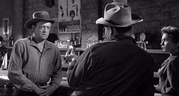 Movie still from “3:10 to Yuma” (1957), directed by Delmer Daves – Two men in hats are standing in front of a bar; Medium shot, Over the shoulder angle