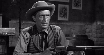 Movie still from “3:10 to Yuma” (1957), directed by Delmer Daves – An old photo of a man holding a gun; Close Up shot, Over the shoulder angle