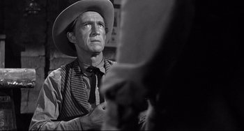 Movie still from “3:10 to Yuma” (1957), directed by Delmer Daves – A man wearing a cowboy hat looking up at another man; Close Up shot, Over the shoulder angle