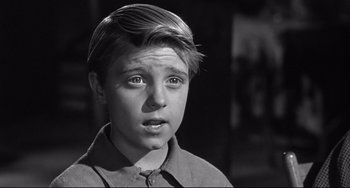 Movie still from “3:10 to Yuma” (1957), directed by Delmer Daves – A young boy is looking at the camera; Close Up shot, High angle