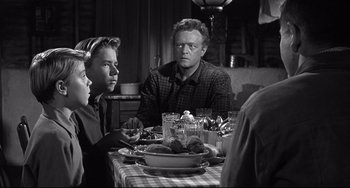 Movie still from “3:10 to Yuma” (1957), directed by Delmer Daves – A group of people sitting at a table with food on it; Medium shot, Over the shoulder angle
