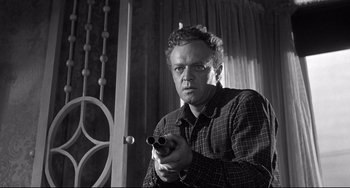 Movie still from “3:10 to Yuma” (1957), directed by Delmer Daves – A black and white photo of a man holding a gun; Medium shot, Low angle