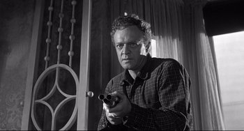 Movie still from “3:10 to Yuma” (1957), directed by Delmer Daves – A black and white photo of a man holding a gun; Medium shot, Low angle