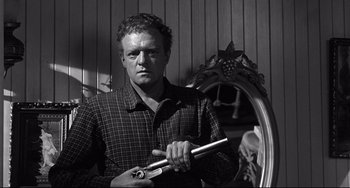 Movie still from “3:10 to Yuma” (1957), directed by Delmer Daves – A black and white photo of a man holding a pipe; Medium shot, Low angle