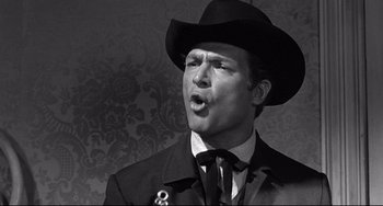 Movie still from “3:10 to Yuma” (1957), directed by Delmer Daves – A man wearing a black hat and a black suit; Close Up shot, Low angle