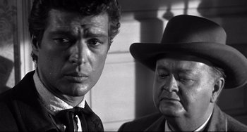 Movie still from “3:10 to Yuma” (1957), directed by Delmer Daves – A man and a man wearing a hat; Close Up shot, Over the shoulder angle
