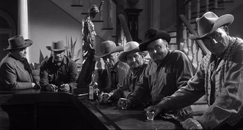 Movie still from “3:10 to Yuma” (1957), directed by Delmer Daves – A black and white photo of men sitting at a bar; Medium shot, Low angle