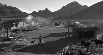 Movie still from “3:10 to Yuma” (1957), directed by Delmer Daves – A man walking a dog in a field with mountains in the background; Extreme Wide shot, High angle