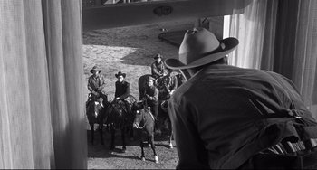 Movie still from “3:10 to Yuma” (1957), directed by Delmer Daves – A black and white photo of men on horses; Wide shot, Over the shoulder angle