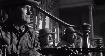 Movie still from “3:10 to Yuma” (1957), directed by Delmer Daves – A group of men sitting next to each other on steps; Medium shot, Low angle