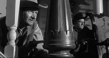 Movie still from “3:10 to Yuma” (1957), directed by Delmer Daves – A man holding a gun while standing next to another man holding a gun; Medium shot, Low angle