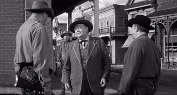 Movie still from “3:10 to Yuma” (1957), directed by Delmer Daves – A group of men standing next to each other on a sidewalk; Medium shot, Over the shoulder angle