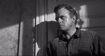 Movie still from “3:10 to Yuma” (1957), directed by Delmer Daves – A black and white photo of a man in a plaid shirt; Close Up shot, Over the shoulder angle