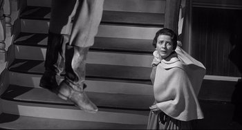 Movie still from “3:10 to Yuma” (1957), directed by Delmer Daves – An old photo of a woman standing next to stairs; Medium shot, Low angle