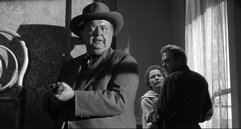 Movie still from “3:10 to Yuma” (1957), directed by Delmer Daves – An older man wearing a suit and a hat standing in front of two other people; Medium shot, Over the shoulder angle
