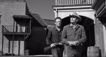 Movie still from “3:10 to Yuma” (1957), directed by Delmer Daves – A couple of men standing next to each other holding guns; Medium shot, Low angle