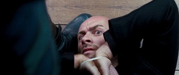 Movie still from “4.3.2.1.” (2010), directed by Mark Davis – A bald man is laying on the ground with his hands on his head; Close Up shot, Overhead angle