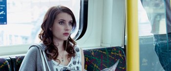 Movie still from “4.3.2.1.” (2010), directed by Mark Davis – A woman sitting on a train listening to music; Close Up shot, High angle