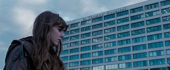 Movie still from “4.3.2.1.” (2010), directed by Mark Davis – A woman standing in front of a large building; Close Up shot, Low angle