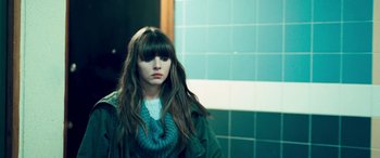 Movie still from “4.3.2.1.” (2010), directed by Mark Davis – A woman with long brown hair wearing a green jacket; Close Up shot, Over the shoulder angle