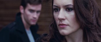 Movie still from “4.3.2.1.” (2010), directed by Mark Davis – A person with a man in the background; Close Up shot, Over the shoulder angle