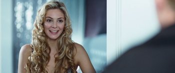 Movie still from “4.3.2.1.” (2010), directed by Mark Davis – A beautiful blonde woman with long hair smiling for the camera; Close Up shot, Over the shoulder angle