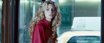 Movie still from “4.3.2.1.” (2010), directed by Mark Davis – A woman with long blonde curly hair wearing a red jacket; Close Up shot, Over the shoulder angle
