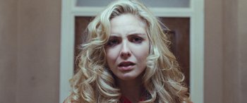 Movie still from “4.3.2.1.” (2010), directed by Mark Davis – A woman with long blonde curly hair looking at the camera; Close Up shot, Low angle