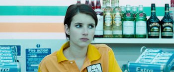 Movie still from “4.3.2.1.” (2010), directed by Mark Davis – A woman in an orange and yellow shirt looking to her left; Close Up shot, Over the shoulder angle