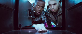 Movie still from “4.3.2.1.” (2010), directed by Mark Davis – Two men are looking at the camera while holding a napkin in front of them; Close Up shot, Low angle