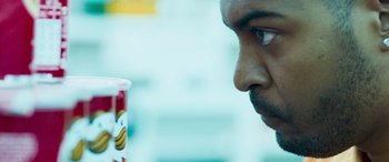 Movie still from “4.3.2.1.” (2010), directed by Mark Davis – A person looking at a container; Extreme Close Up shot, Over the shoulder angle