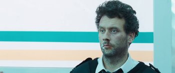 Movie still from “4.3.2.1.” (2010), directed by Mark Davis – A person wearing a suit and tie; Close Up shot, Low angle