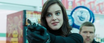 Movie still from “4.3.2.1.” (2010), directed by Mark Davis – A beautiful young woman holding a camera and wearing gloves; Close Up shot, Over the shoulder angle