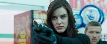 Movie still from “4.3.2.1.” (2010), directed by Mark Davis – A beautiful woman holding a gun while wearing gloves; Close Up shot, Low angle