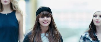 Movie still from “4.3.2.1.” (2010), directed by Mark Davis – A woman with long brown hair wearing a black headband; Close Up shot, Over the shoulder angle